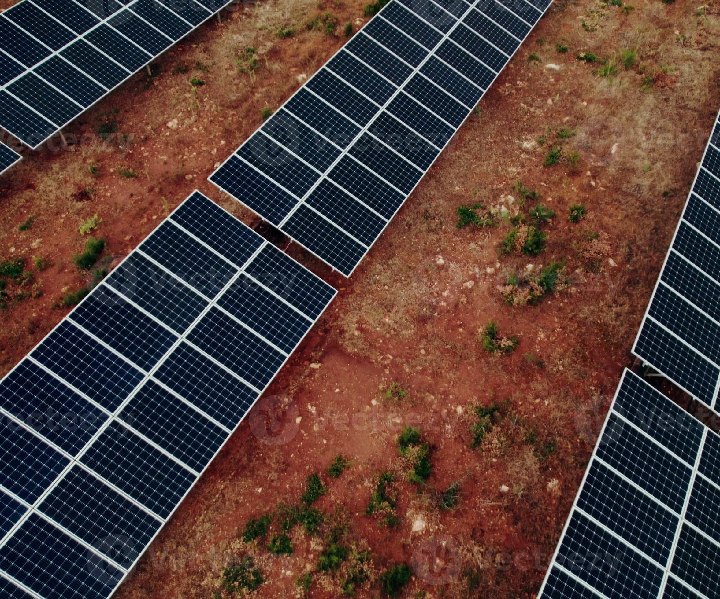 Top-down aerial of the Remote Defence Facility solar array showing rows of photovoltaic panels arranged diagonally across red outback dirt with sparse vegetation